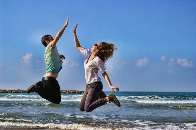 jumping enjoy hifive man woman jump sea wave sky smile laugh waves