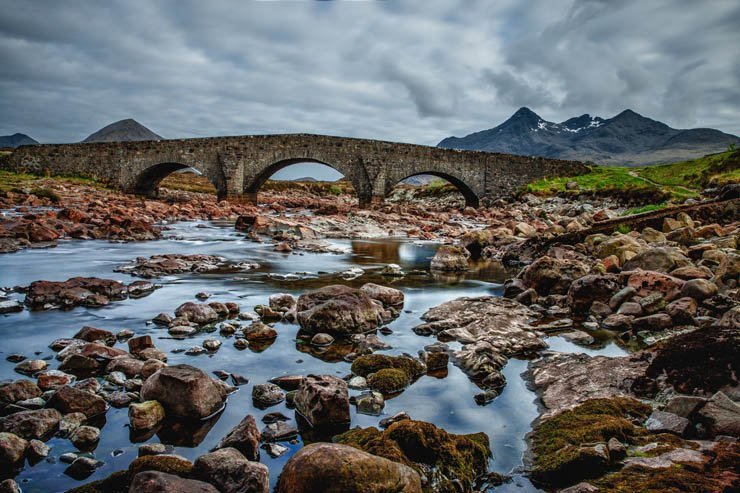 mountain bridge stones rocks lake shore sea water